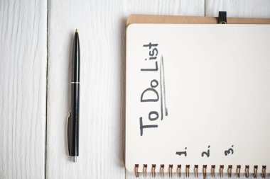Yapılacaklar listesi harfleri ve tahta arka planda kalemi olan dizüstü bilgisayar görünümü