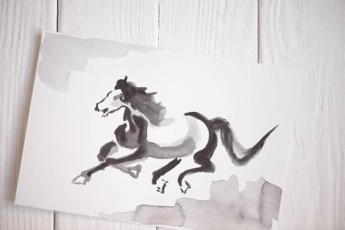Top view of paper with Japanese painting with horse on wooden background clipart