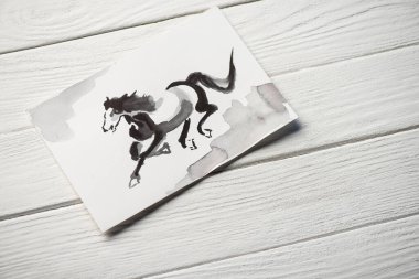 Tahta arka planda at resmi olan Japon resimli kağıdın üst görüntüsü.