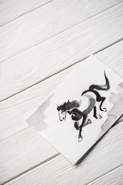 Tahta arka planda gri atı olan Japon resimli kağıdın üst görüntüsü.