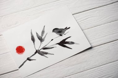 Japon resimli kağıdın yüksek açılı görüntüsü dalında kuş ve ahşap zeminde güneş.