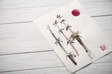 Japon resimli, bambu, güneş ve ahşap arka planda mühür içeren yüksek açılı kağıt manzarası.