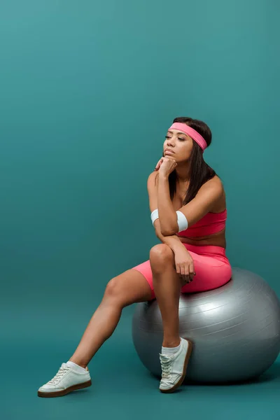 Pensativa Deportista Afroamericana Sentada Una Pelota Fitness Sobre Fondo Verde — Foto de Stock