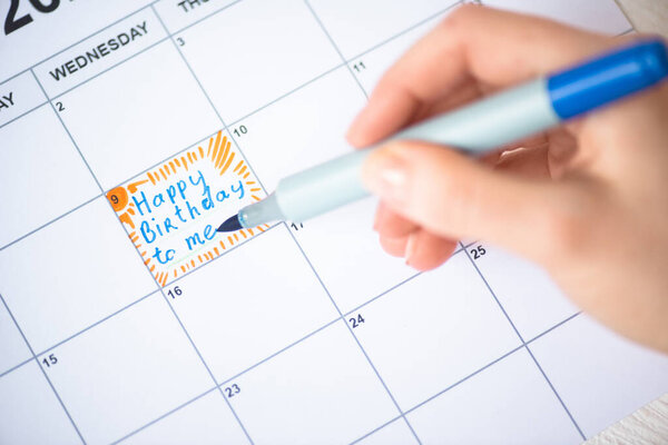 Cropped view of woman pointing with marker pen on happy birthday to me lettering in to-do calendar 