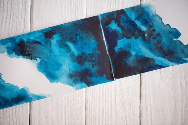 Top view of pictures with Japanese painting with blue watercolor on wooden background