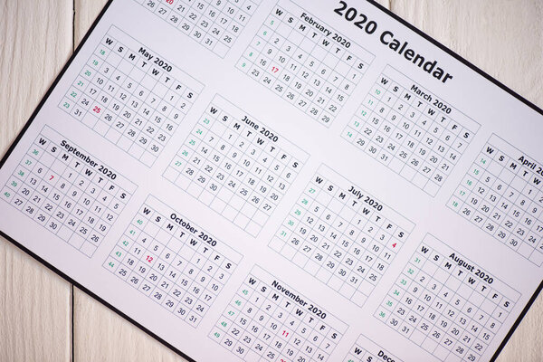 Top view of 2020 calendar on wooden background