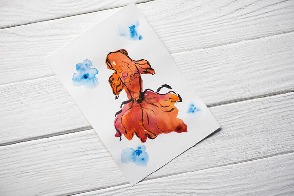 Top view of paper with Japanese painting with fish on wooden background