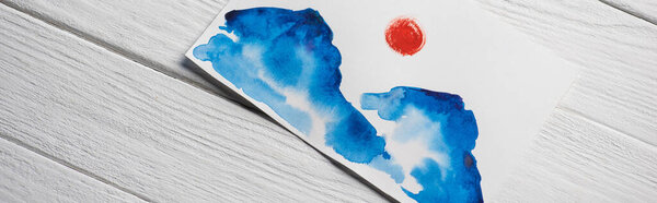 Top view of paper with Japanese painting with clouds and sun on wooden background, panoramic shot