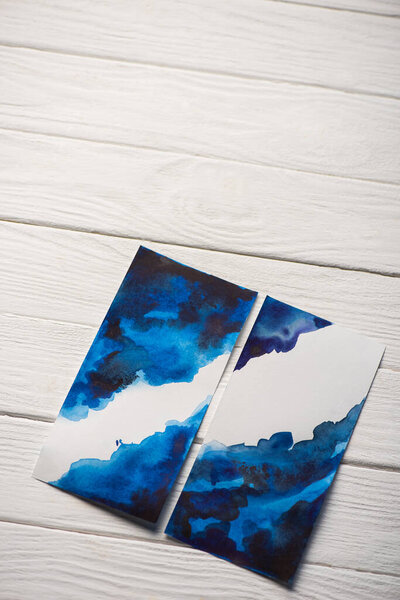 High angle view of paper with japanese painting with bright blue watercolor on wooden surface