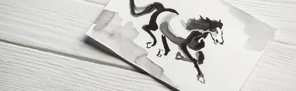 Top view of paper with japanese painting with horse on wooden background, panoramic shot