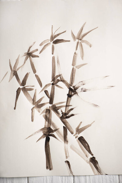 Top view of paper with japanese painting with bamboo on wooden background