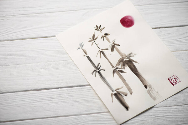 Высокий угол обзора бумаги с японской росписью с бамбуком, солнцем и печатью на деревянном фоне
