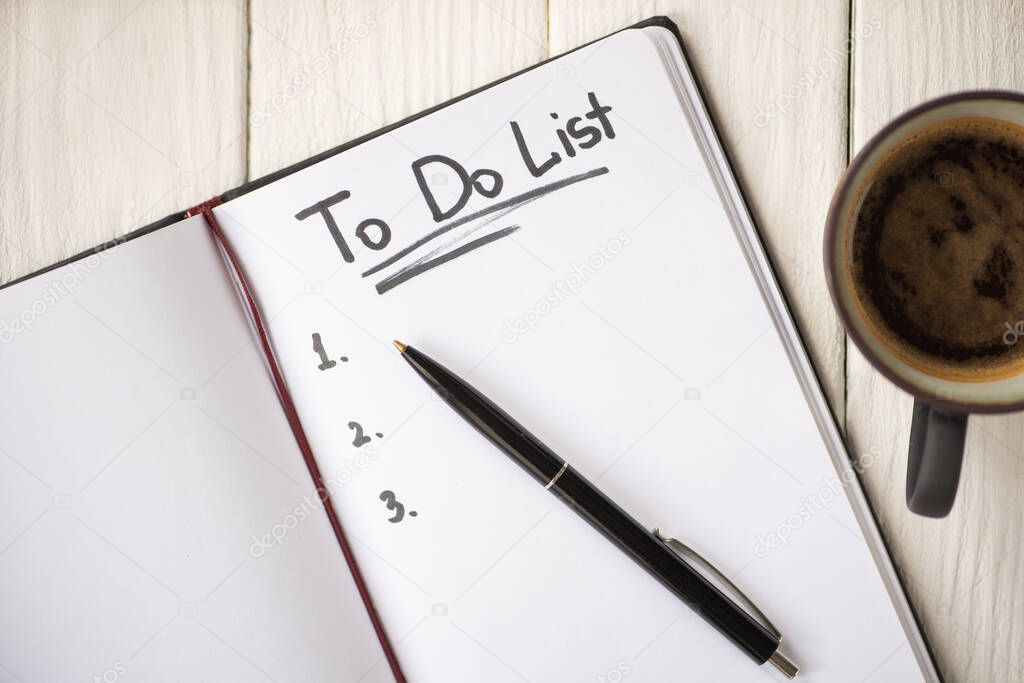 Top view of notebook with do list lettering and pen near cup of coffee on wooden background