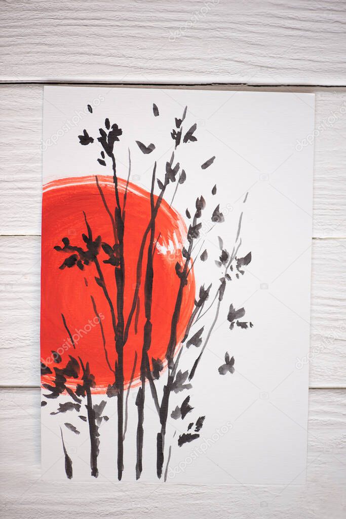 Top view of paper with Japanese painting with red sun and branches on wooden background