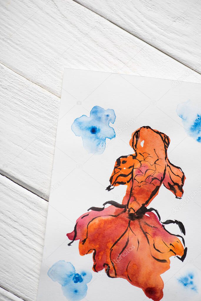 Top view of paper with Japanese painting with orange fish on wooden background