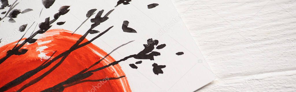 Top view of paper with Japanese painting with red sun and branches on wooden background, panoramic shot