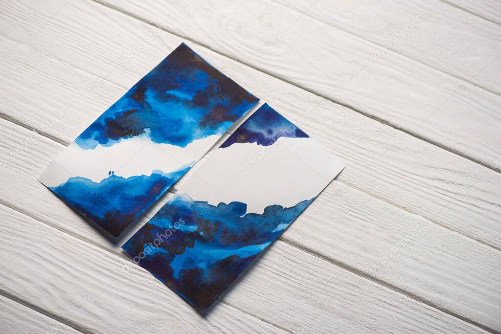 High angle view of paper with japanese painting with bright blue watercolor on wooden background