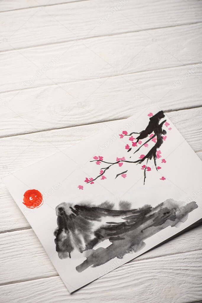 High angle view of paper with japanese painting with sun, Sakura branches and hill on wooden background