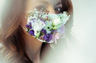 Çiçek maskeli çekici bir kadının seçici odağı beyaz kameraya bakıyor.
