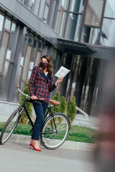 Selective Focus Businesswoman Plaid Mask Holding Newspaper Standing Bicycle — Stock Photo, Image