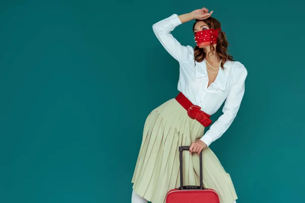 Menina Elegante Máscara Vermelha Posando Perto Saco Viagem Isolado Azul — Fotografia de Stock