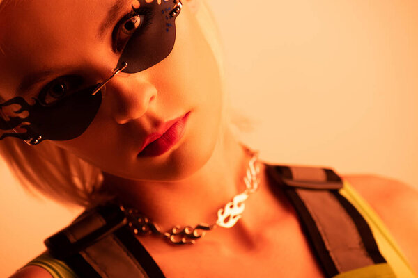 привлекательная футуристическая модель, позирующая в огнеобразных солнцезащитных очках на оранжевом
