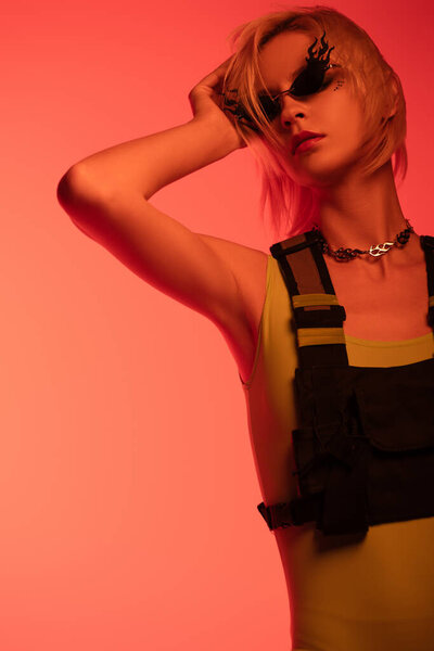 fashionable attractive girl posing in fire-shaped sunglasses on red