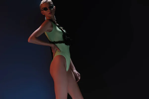 Mooie Modieuze Vrouw Futuristisch Bodysuit Vuurvormige Zonnebril Poserend Donker — Stockfoto