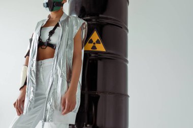 cropped view of futuristic african american woman in safety mask near radioactive waste barrels isolated on white clipart