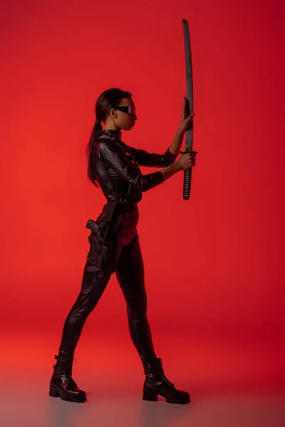 赤を背景に剣を持った眼鏡をかけた未来的なアフリカ系アメリカ人女性の — ストック写真