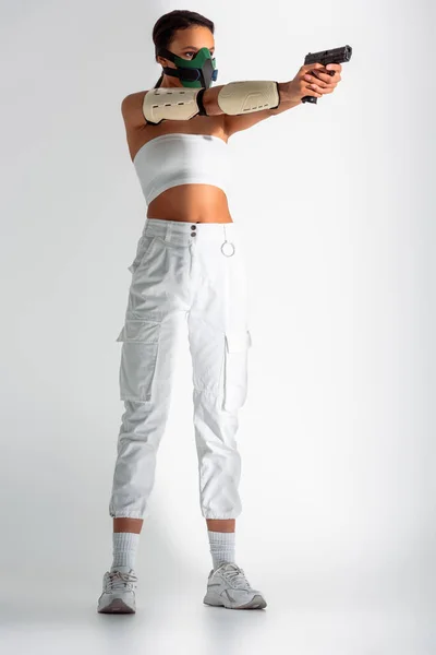 Futuristica Donna Afroamericana Maschera Sicurezza Mirando Pistola Sfondo Bianco — Foto Stock
