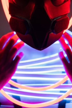 close up view of futuristic african american woman in respirator and neon lighting clipart