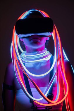 VR kulaklıklı ve neon ışıklı fütürist Afrikalı Amerikalı kadın.
