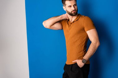 Şortlu yakışıklı adam, gri ve mavi üzerine kahverengi polo. 