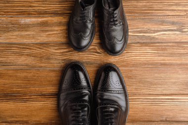 Top view of mens and childrens black elegant shoes on wooden background, fathers day concept clipart