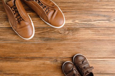 Top view of mens and childrens brown casual shoes on wooden background, fathers day concept clipart