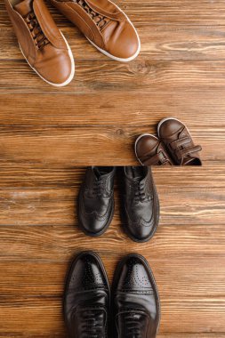 Split image with mens and childrens brown and black shoes on wooden background, fathers day concept clipart