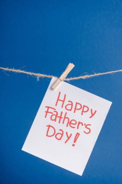 White greeting card with red lettering happy fathers day hanging on rope with clothespins isolated on blue clipart