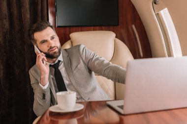 Yakışıklı iş adamının seçici odak noktası özel bir uçakta akıllı telefondan konuşmak.