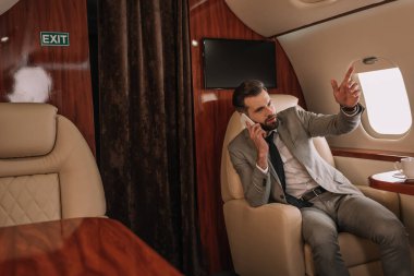 Akıllı telefondan konuşan ve özel jeti işaret eden yakışıklı bir iş adamı.