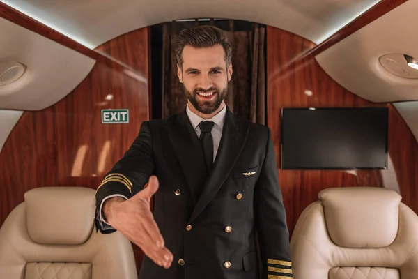 Przystojny Pilot Uśmiecha Się Kamery Stojąc Wyciągniętą Ręką — Zdjęcie stockowe