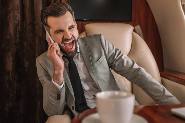 Hombre Negocios Enojado Gritando Teléfono Inteligente Mientras Vuela Jet Privado — Foto de Stock