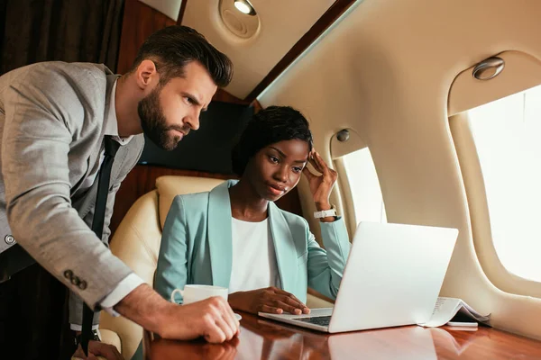 Dos Empresarios Multiculturales Mirando Computadora Portátil Mientras Viaja Jet Privado — Foto de Stock