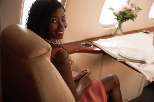 Hermosa Mujer Afroamericana Sentada Cerca Mesa Servida Jet Privado Sonriendo — Foto de Stock