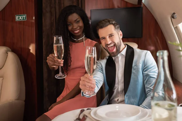 Alegre Elegante Pareja Interracial Sosteniendo Copas Champán Mientras Mira Cámara — Foto de Stock