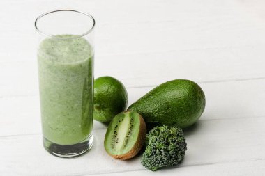 kivi, brokoli, avokado ve beyaz ahşap yüzeyde limonlu yeşil smoothie.