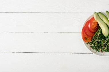 Beyaz ahşap yüzeyde domates, avokado ve mikroyeşil kabın içinde.