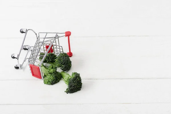Verse Groene Broccoli Verstrooid Uit Winkelwagen Wit Houten Oppervlak — Stockfoto