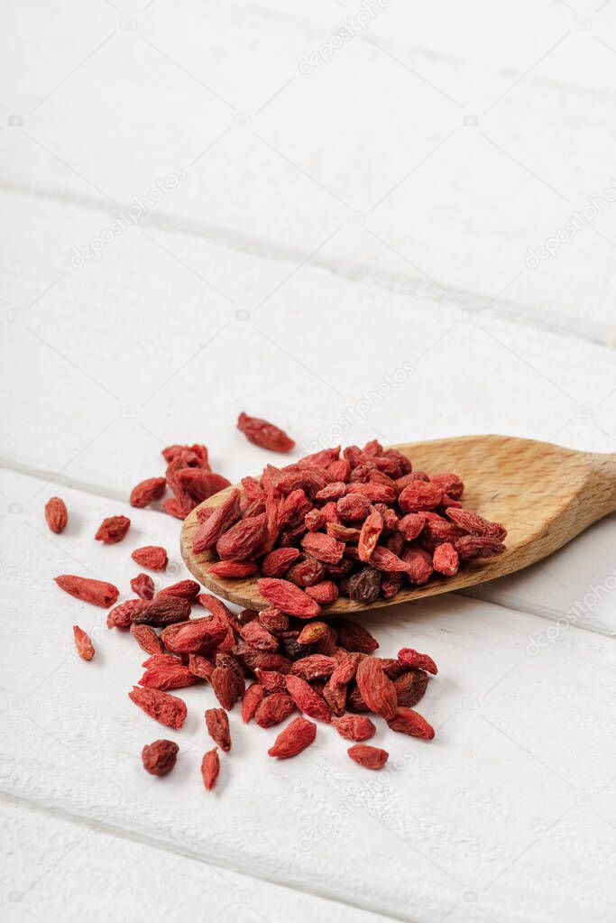 dry goji berries in wooden spoon on white table