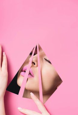 Woman with pink lips and closed eyes across triangular holes touching paper on black  clipart